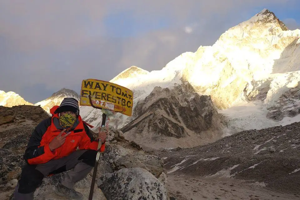 a person holding a sign in front of a snowy mountain